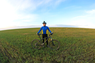 cyclist with Bicycle standing on field path