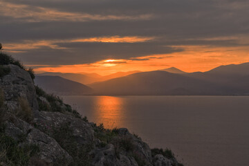 Fototapeta na wymiar Sunset over the Argolic Gulf with cliff in foreground, Nafplion, Greece