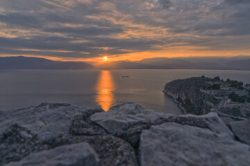 Rocks in the foreground with sunset over the Argolic Gulf, Nafplion, Greece