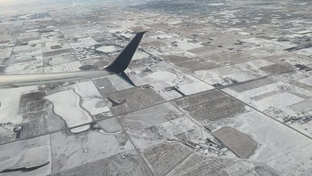 The view of a plane wing as it flies low over Calgary, Alberta, Canada. An airplane in the air over the rural area near a big city. 