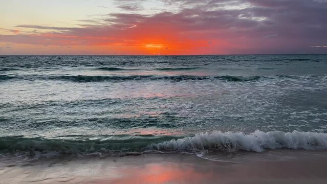 Sunrise over the sea and beach with beautiful landscape in Riviera Maya, Mexico. Sun above the water in the early morning over the Caribbean sea with gentle waves hitting the sand.