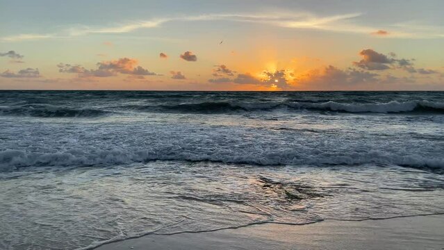 Sunrise over the sea and beach with beautiful landscape in Riviera Maya, Mexico. Sun above the water in the early morning over the Caribbean sea with gentle waves hitting the sand.