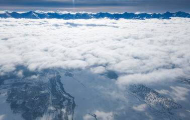 Transylvania under the sea of clouds. Winter landscape at the bottom of Fagaras Mountains. Aerial view in a sunny day.