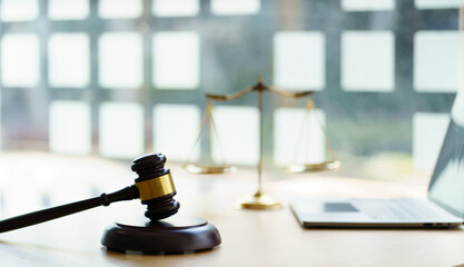 Scales of justice and Gavel on wooden table and Lawyer or Judge working with agreement in Courtroom, Justice and Law concept.