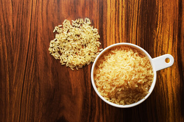 Taza medidora con arroz precocido sobre una mesa de madera. Vista superior.