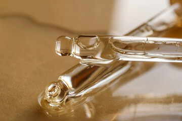 Pipettes with oil or serum on a golden background.