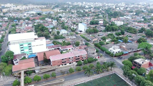 Big city of Yopal with multiple green trees in the neighborhood and a small football stadium in the departement Casanare in Columbia. Drone dolley shot