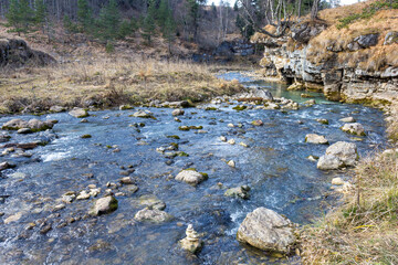 autumn morning, walking along the bed of a mountain river that has become shallow by the beginning...