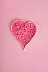 Valentines day composition. Sweet confetti shape of heart on pastel pink background. Top view, flat lay, vertical