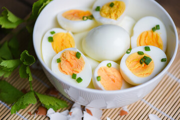 Eggs breakfast, fresh eggs menu food boiled eggs in a bowl decorated with leaves chopped fresh green onions and celery on wooden background, cut in half egg yolks for cooking healthy eating