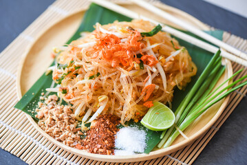 Thai food fried noodle Thai style with prawns bean sprout and garnish peanuts chili powder sugar lemon lime, Stir-fry noodle Pad Thai on plate served on the dining table food - top view