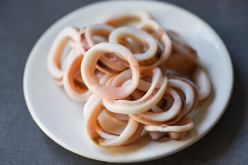 squid rings on white plate, Fresh squid cooked boiled with lettuce vegetable salad on dark background