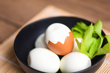 Eggs breakfast, fresh peeled eggs menu food boiled eggs in a bowl decorated with leaves green celery on wooden background, egg cooking healthy eating concept