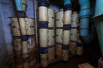 iron cans stored in a damp basement. shelter water equipment. pipes for ventilation and water supply
