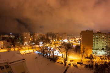 night city view with yellow lanterns in winter. streets from above with snow