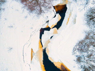 Aerial top down view of a frozen river in snowy landscape. Winter season concept