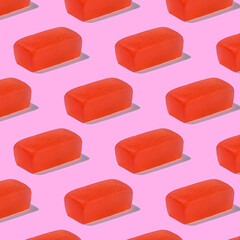 Red marmalade jelly candies on a pink background creating a repeating pattern.