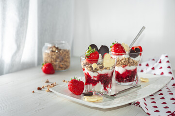 Sweet milk dessert on Valentine's Day. Delicious strawberry yogurt decorated with heart-shaped chocolate on a wooden table. Side view. Selective focus. Healthy breakfast.