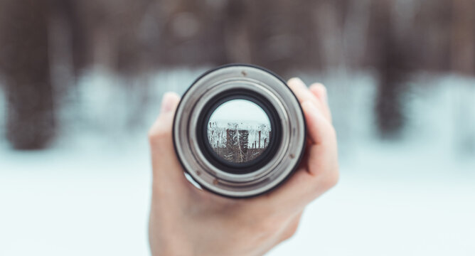 Looking to the frozen lake in middle of forest through lens. Point of view. Selective focus.
