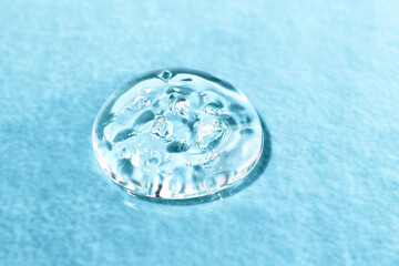 A drop of transparent body care cosmetic product, spa treatments on a colored background, copy space. Serum hyaluronic acid with bubbles close-up, top view.