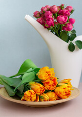 bouquet of spring yellow tulips on wooden plate, pink roses are in a bailer, garden flowers, flower shop layout