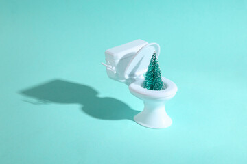 Mini toilet with a Christmas tree on a blue background. Minimal christmas concept