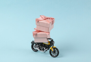 Toy motorcycle with gift boxes on blue background. Minimal holiday layout