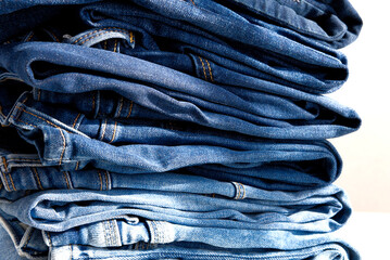 a pile of blue jeans on a white background. Sunlight. Close up