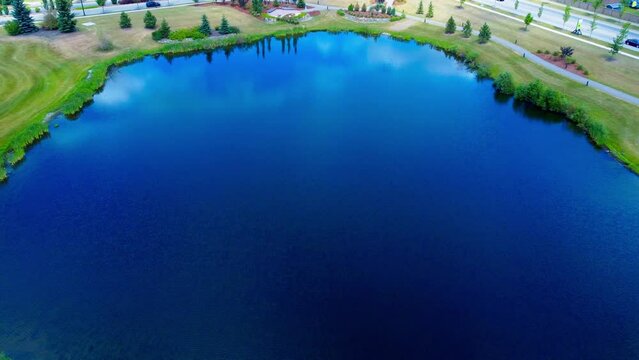 golf course aerial flyover reflective birds top eye view over garden waterfall tiered from pond to pond closeup shore pathway next to roadway in the Southside of Edmonton Alberta Canada
