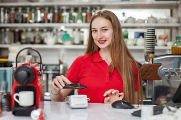 Young smiling woman barista making coffee