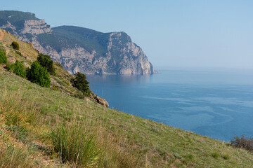 Mountains illuminated sea Balaclava. Light atmospheric spring landscape. View of high cliffs with green trees, blue sky, solar reflections. The concept of travel, active recreation, relaxation, walks
