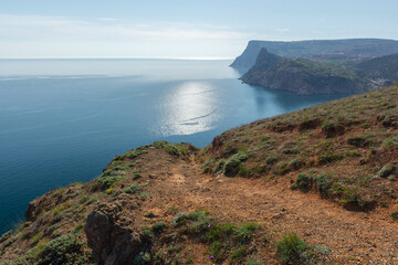 Fototapeta na wymiar Mountains illuminated sea Balaclava. Light atmospheric spring landscape. View of high cliffs with green trees, blue sky, solar reflections. The concept of travel, active recreation, relaxation, walks