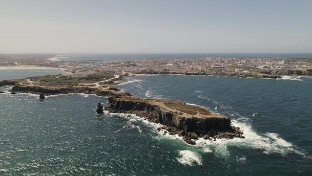 Aerial orbiting view Rocky Papoa islet revealing Peniche village Peninsula. Portugal