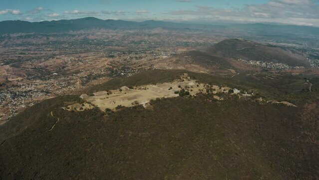 Aerial rotating shot over the Zapotecs Ancient Mesoamerican Pyramids,Monte Alban, Chiapas, Mexico with a beautiful mountain range in the background.