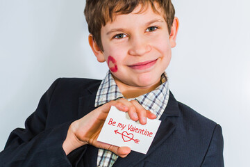 A teenage boy holds a card with a heart in his hand. Boy wishes happy Valentine's day