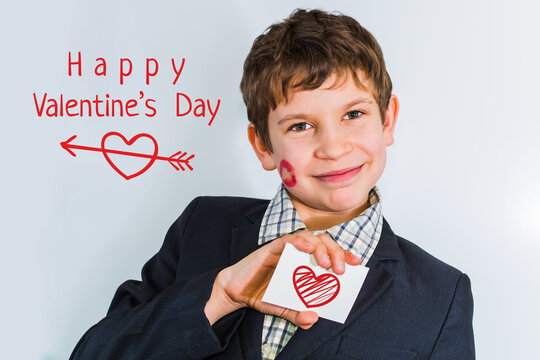 A teenage boy holds a card with a heart in his hand. Boy wishes happy Valentine's day