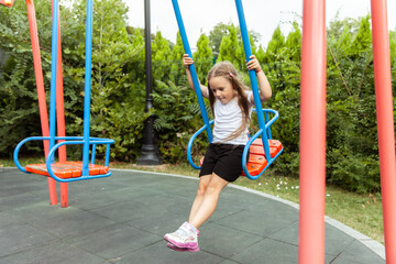 Little cute girl riding a swing outdoors