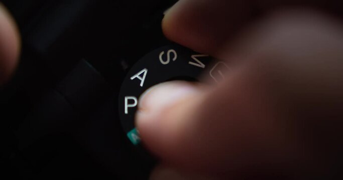 Close up video person changing the mode dial or camera dial on a sony camera from auto to Manual