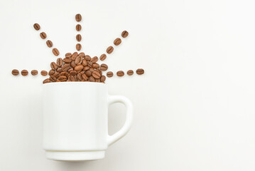 Cup and grains of coffee in the shape of the sun on a light background.