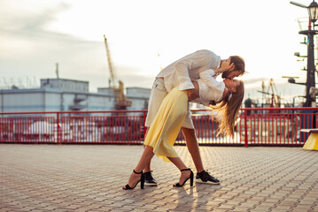 Young couple in love, man and woman kissing at sunset in the seaport. Romantic love concept