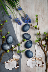 White bunnies, painted easter eggs, muscari and spring branch  