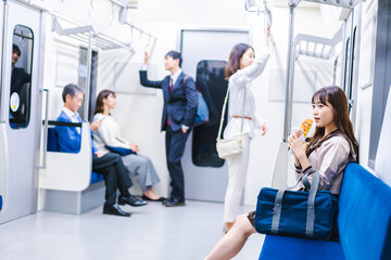 電車でパンを食べる学生