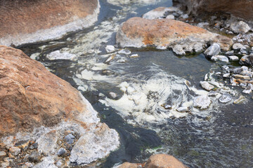 Close up shot of clear and clean water flow stream in natural hot spring during summer time shows beautiful water surface and colorful rock. It is destination for tourist visiting on vacation.