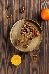 A piece of tangerine pie with walnuts on a wooden table. Sugar, gluten and lactose free, vegan. Vertical orientation, top view.