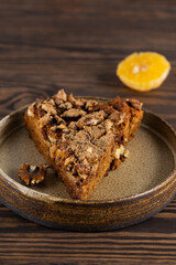 A piece of tangerine pie with walnuts on a wooden table.