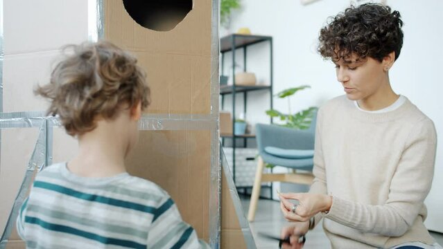 Portrait of creative young people mother and son decorating handmade spaceship playing at home. Childhood and family leisure time concept.