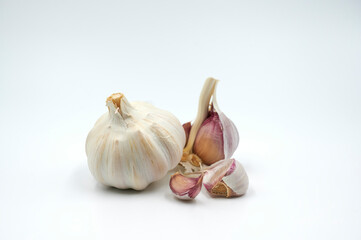 Geschlossene und geöffnete Knoblauchzehe vor weißem Hintergrund