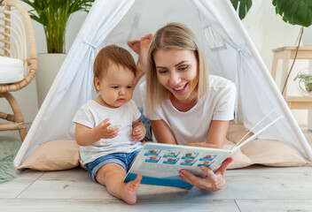 Happy woman mom and her little daughter read book in wigwam at home © splitov27