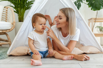 Young mother and little daughter spend time together in a wigwam at home © splitov27