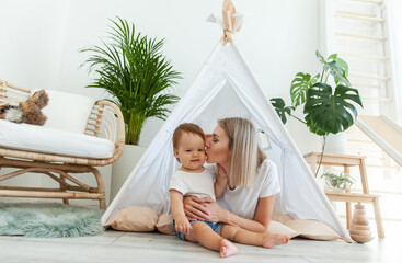 Young mother and little daughter spend time together in a wigwam at home © splitov27